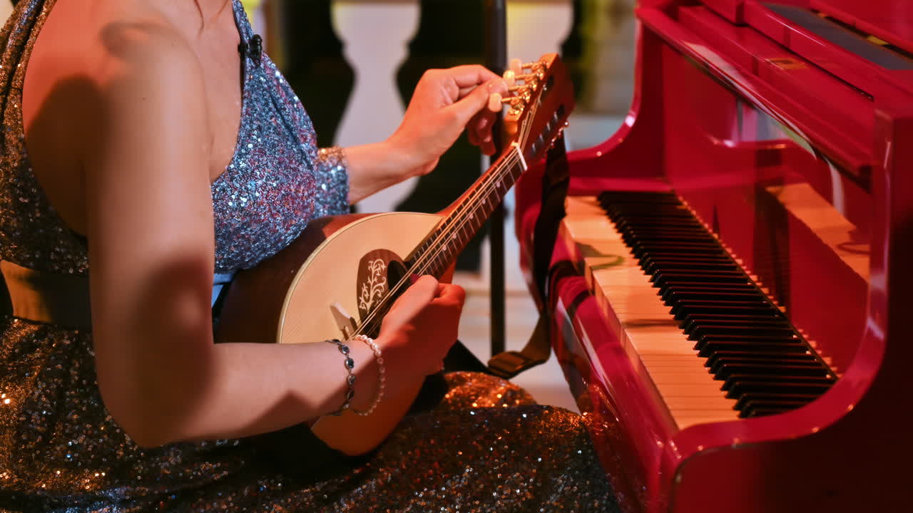 Dressed-up woman playing the mandolin near a red piano