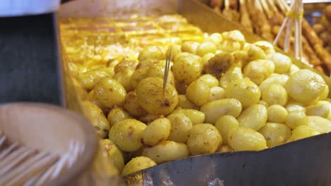 chinese street food counter full of cooked potatoes using a spatula in kuanzhai alley, chengdu, china