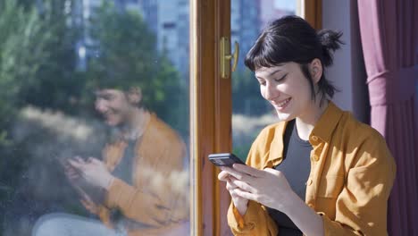 Young-woman-smiling-at-phone-message.