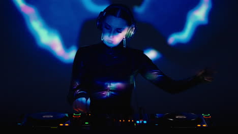 female dj performing on stage with a set of turntables.