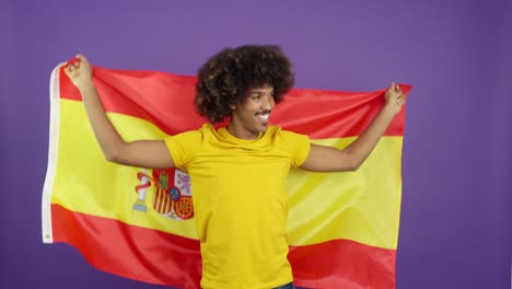 happy man with afro hair wrapped in spanish flag