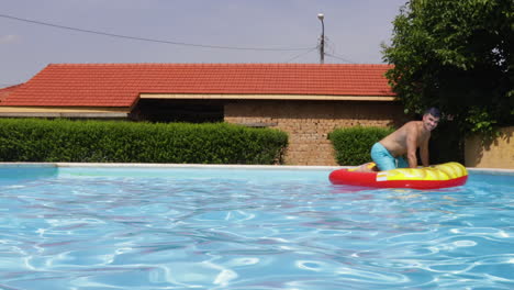 funny man on inflatable pool lounger float in outdoor swimming pool in villa