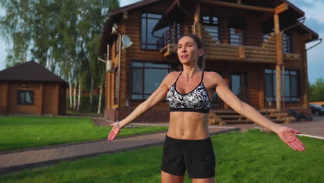 mujer delgada y hermosa en ropa deportiva en el fondo de la casa en el césped realiza saltos para el entrenamiento cardiovascular y la quema de grasa