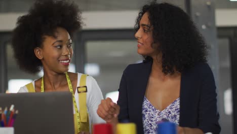 mixed race colleagues sitting in office and discussing work over laptop