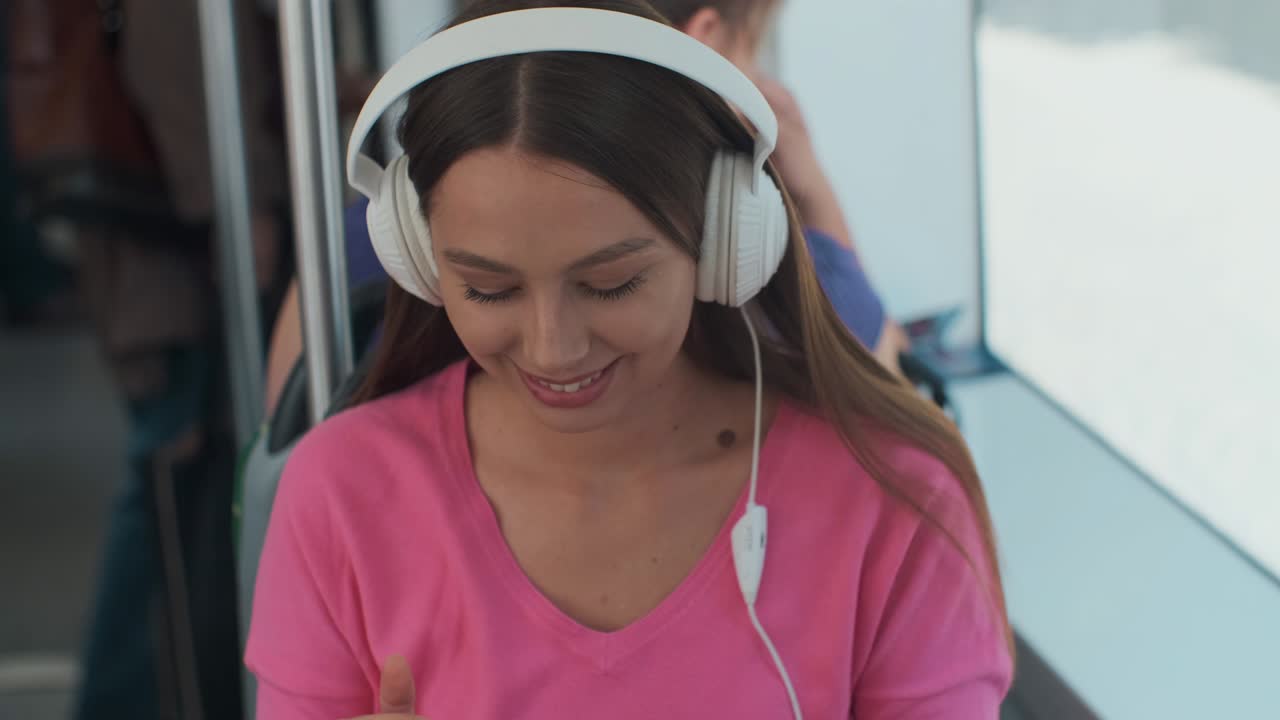 joven pasajera disfrutando de un viaje en el transporte público, sentada con auriculares cerca de la ventana en el tranvía moderno.