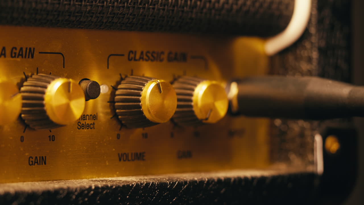 Close-up of plugging a jack into a guitar amplifier and turning up the volume knob, live concert show, playing music on guitar tube amplifier.