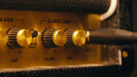 close-up of plugging a jack into a guitar amplifier and turning up the volume knob, live concert show, playing music on guitar tube amplifier.