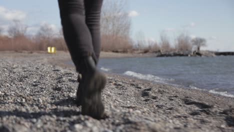 back view of a woman feet walking along the lake shore during sunny day - close up shot