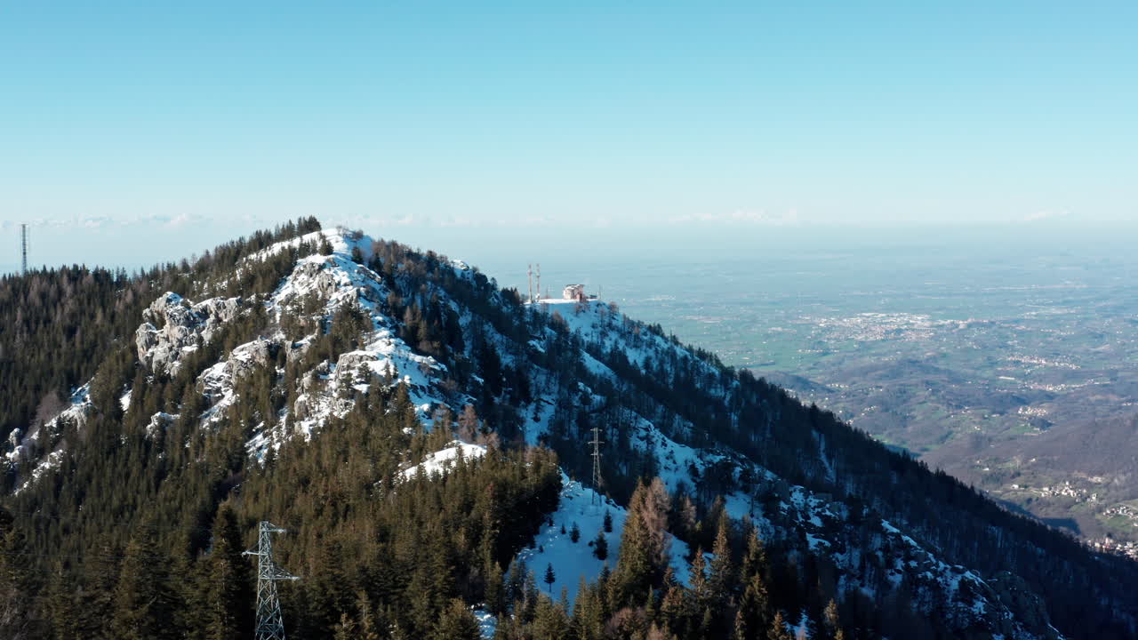 cresta de montaña cubierta de nieve con vista aérea, cielo azul claro, con vistas a un vasto bosque y valle debajo
