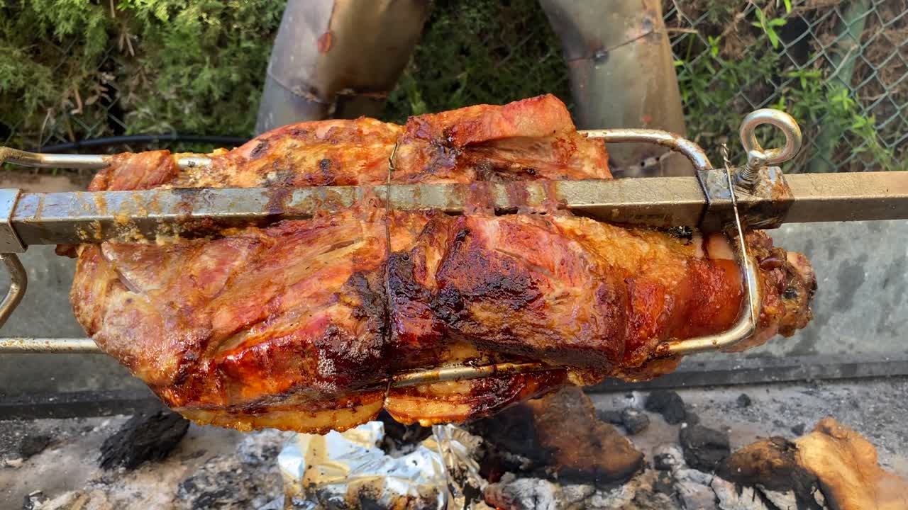 cochinillo asado en un palo giratorio de metal escupido sobre el fuego, piel extra crujiente, parrilla de barbacoa de cerdo, tiro estático de 4k