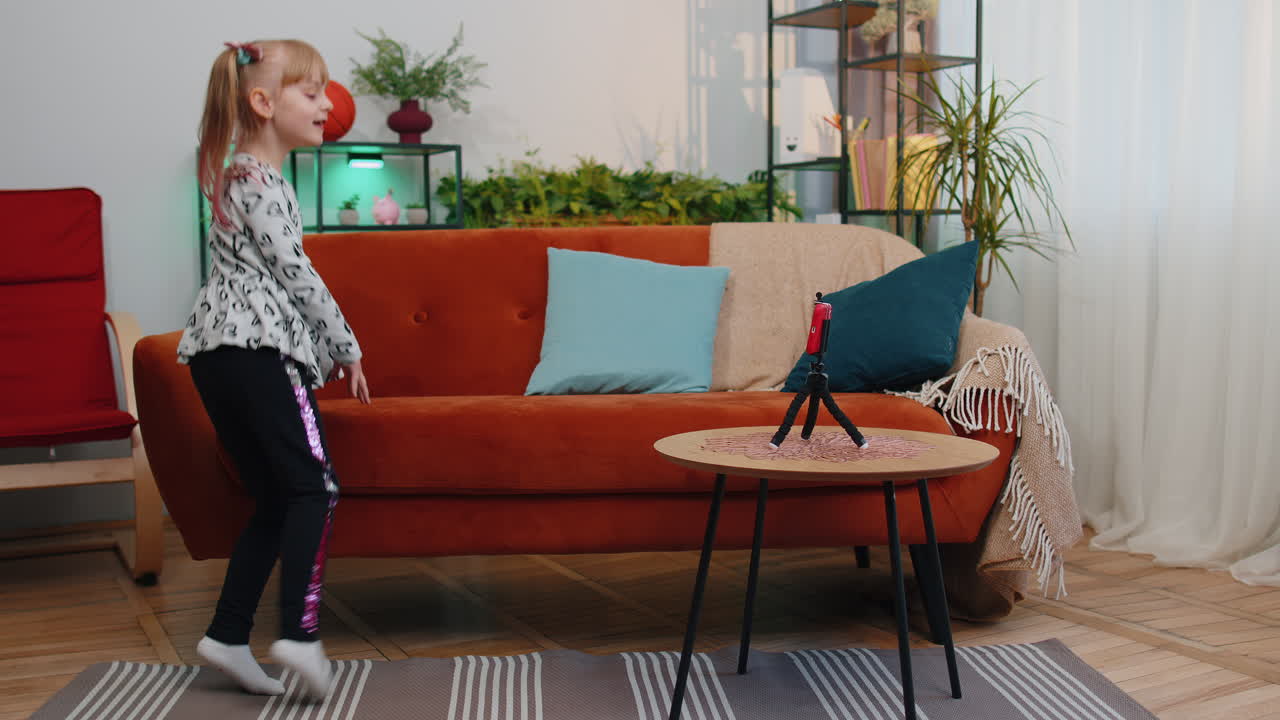 niña blogger influyente haciendo video de baile para la red de redes sociales en el teléfono inteligente en casa