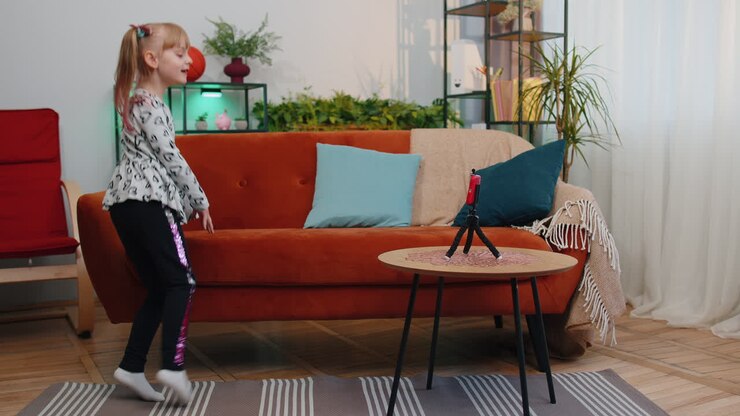Children girl blogger influencer making dance video for social media network on smartphone at home