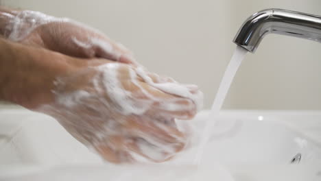 person washing hands with soap in sink, avoid covid-19 coronavirus transmission