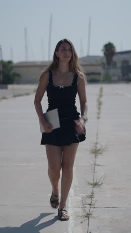 Woman in black top and skirt using a tablet outdoors