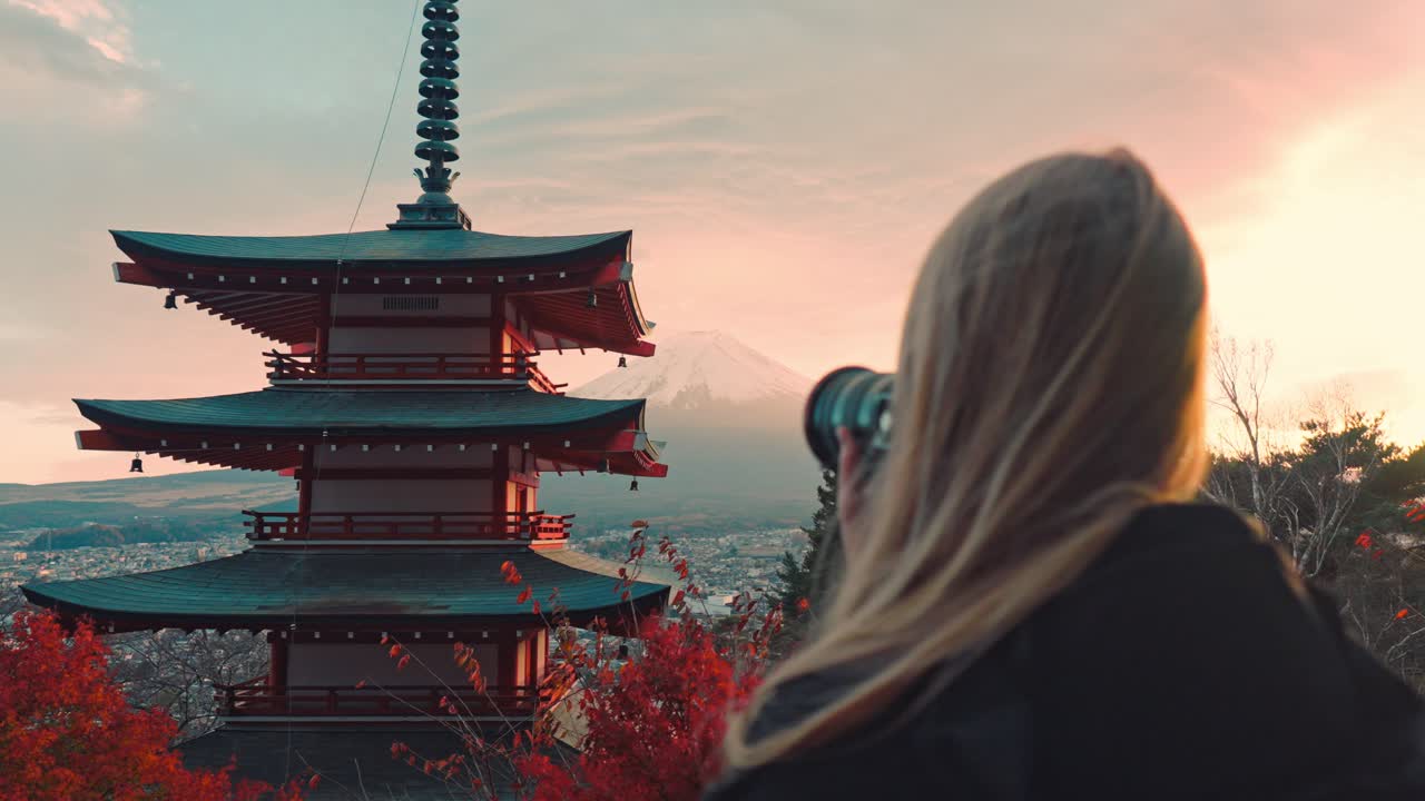 una mujer captura la impresionante vista de la pagoda chureito al atardecer, con el monte fuji en el fondo.
