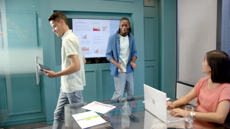 presenting annual report, man standing near screen, colleagues using laptop and tablet