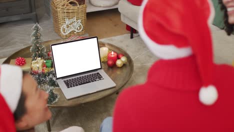 Smiling-diverse-friends-in-santa-hats-making-laptop-christmas-video-call,-with-copy-space-on-screen