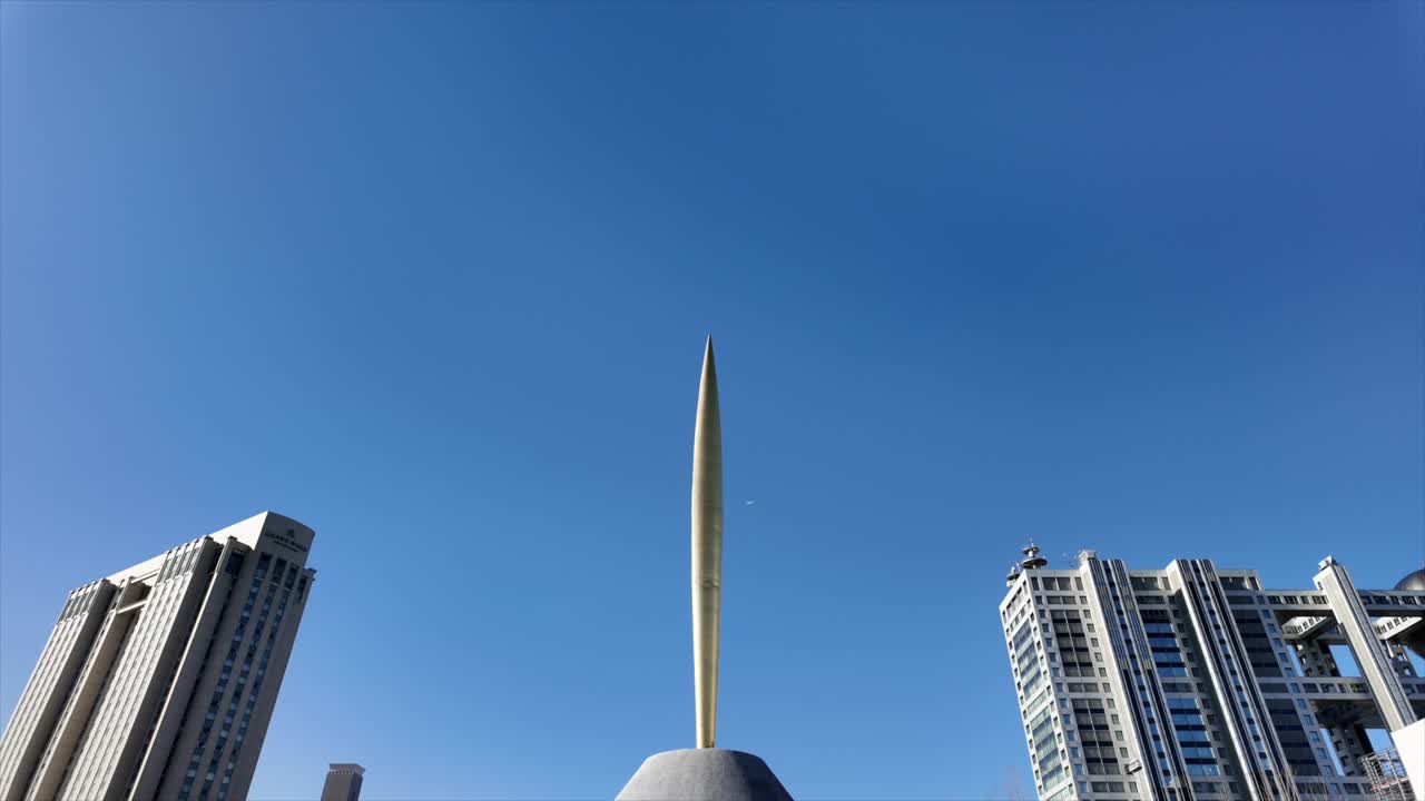 Torre. Filmato cinematografico di un aereo che vola sopra un'alta torre cittadina.