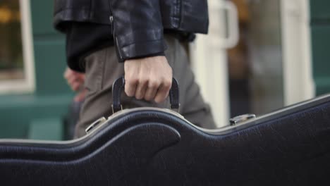 hombre llevando un estuche de guitarra en la ciudad