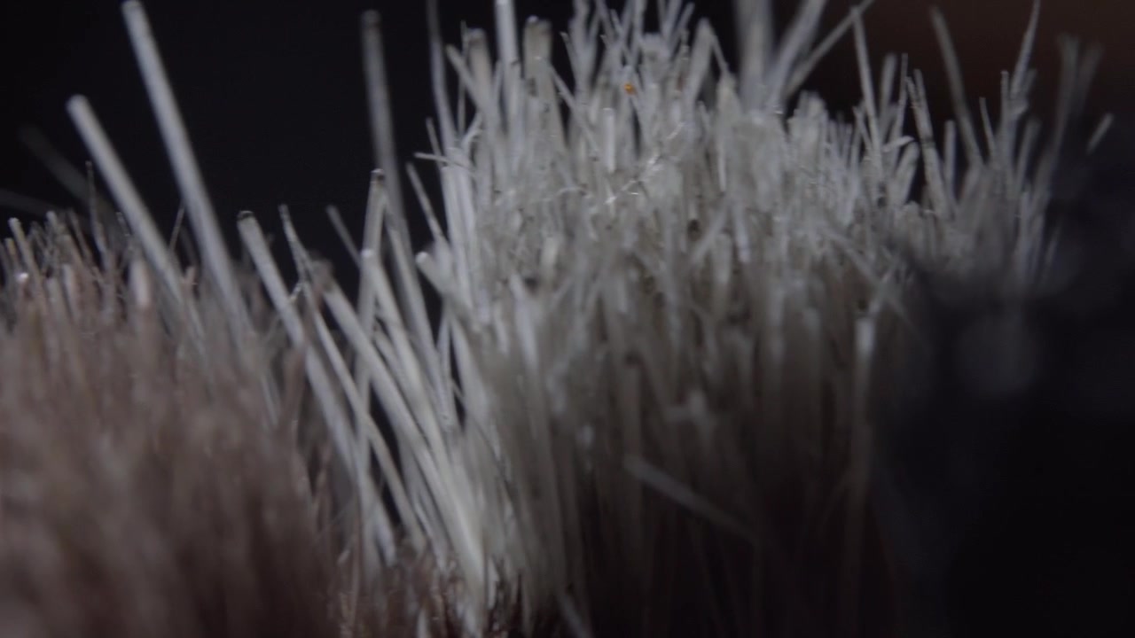 Plan macro panoramique à travers de fines soies synthétiques, mettant en évidence une texture complexe, des fibres superposées et des motifs abstraits avec un mouvement de caméra fluide.