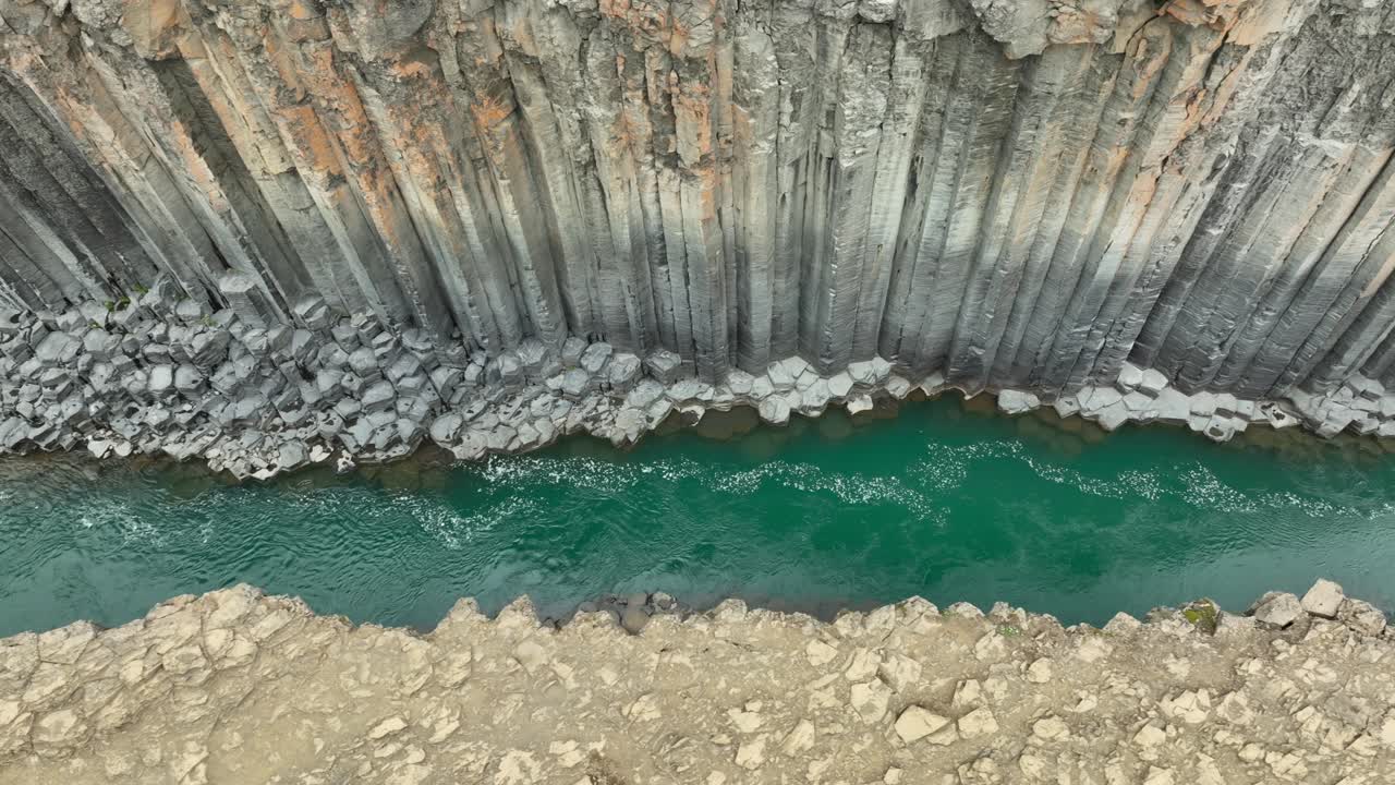 Basalt column and glacial river of Studlagil Canyon on Iceland island. Aerial top down shot. Flowing water of stream