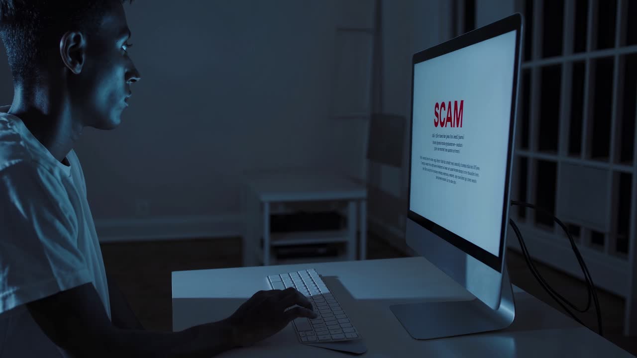 젊은 남자가 밤에 컴퓨터 화면에서 사기를 보고 있습니다.