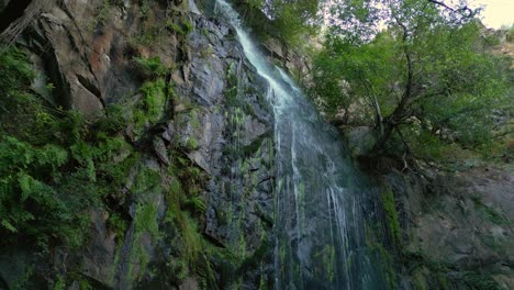 cascade of water on aguacaida waterfall over mossy cliff in panton, spain