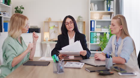 trabajadoras de oficina discuten informes de ventas