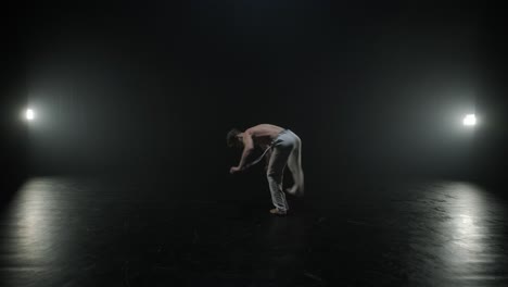 capoeira fighters performing dynamic moves on stage. martial arts, dance, and acrobatics in action. bare-chested athletes showcasing strength, flexibility, and technique under spotlights