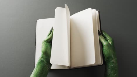 video of halloween green monster hands and notebook with copy space on grey background