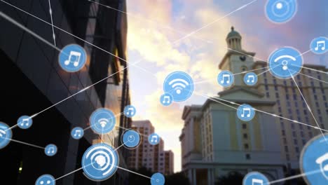 animación de una red de iconos digitales contra una vista de ángulo bajo de edificios altos y cielo.