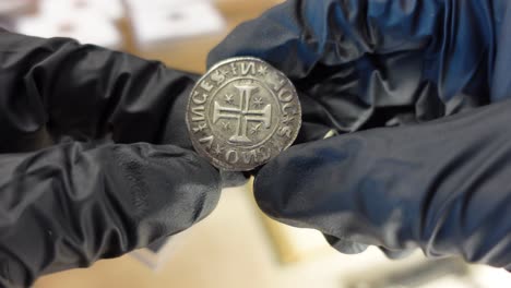 coleccionista examinando una moneda de oro portuguesa de la época medieval