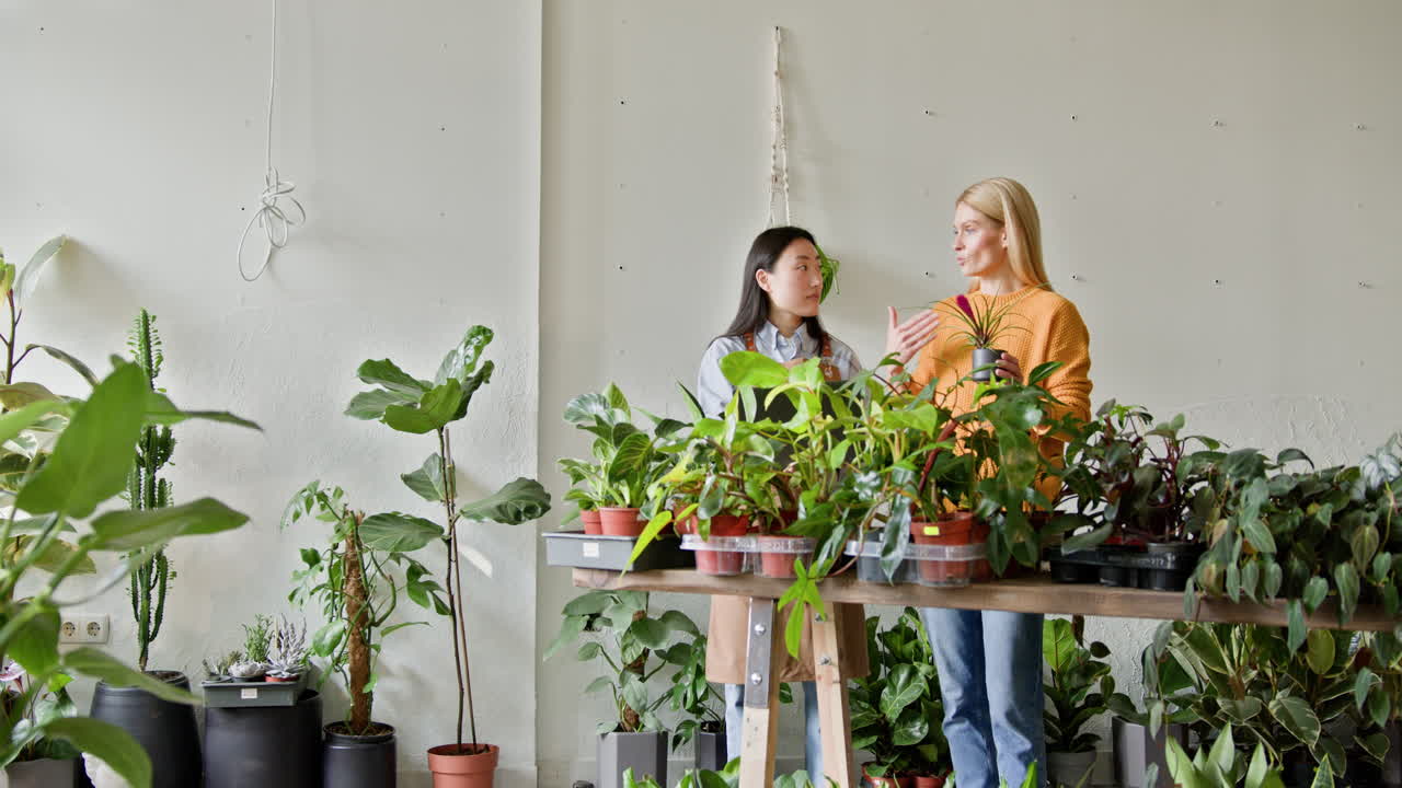 две женщины обсуждают растения в магазине растений.