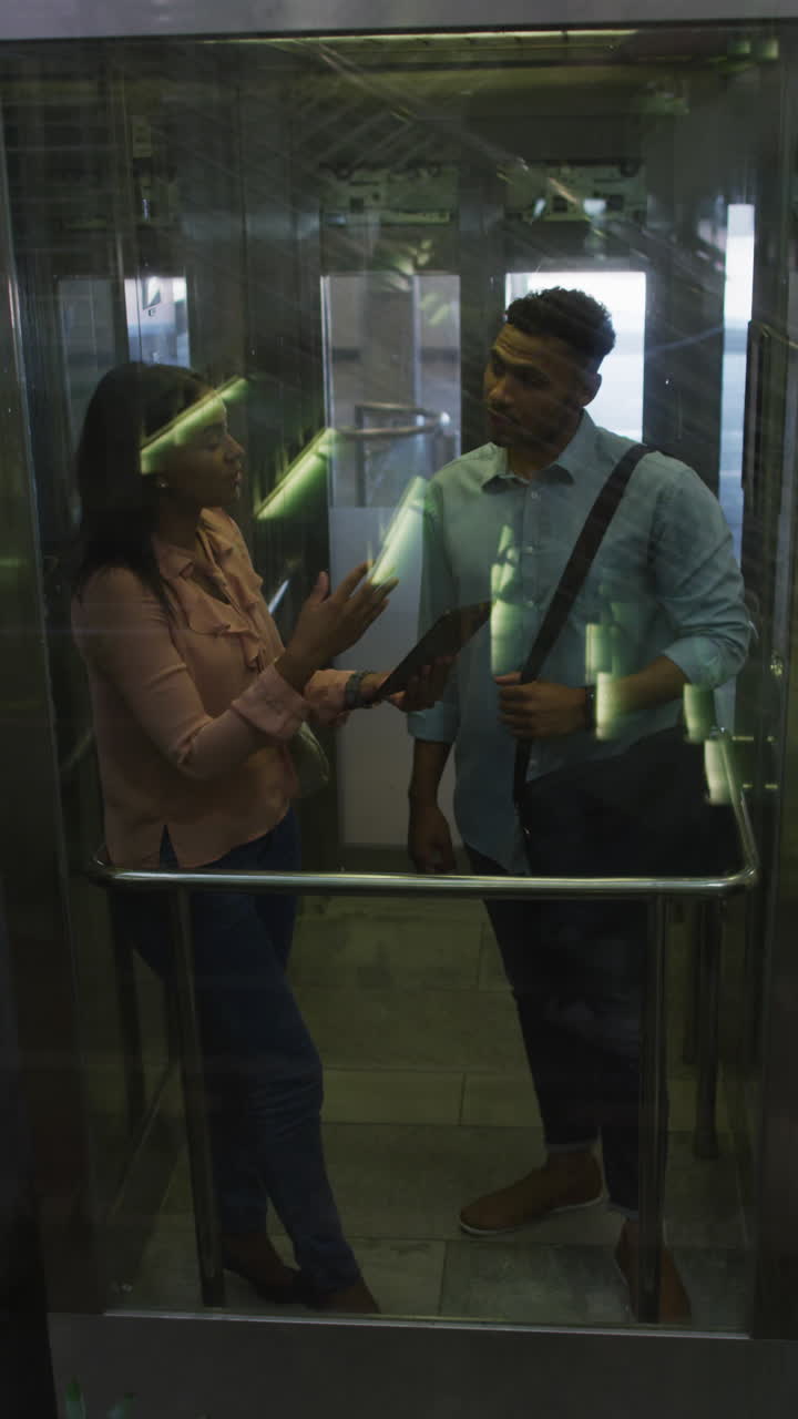 Video vertical de compañeros de trabajo diversos felices hablando en el ascensor