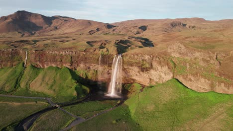 Toma-Aérea-De-La-Cascada-De-Seljalandsfoss-En-Islandia-A-Lo-Largo-De-La-Carretera-De-Circunvalación-Durante-La-Hora-Dorada-Del-Atardecer