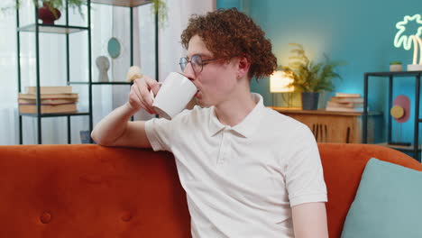 happy young man smelling enjoy drinking cup of beverage hot coffee taking a break relaxing at home