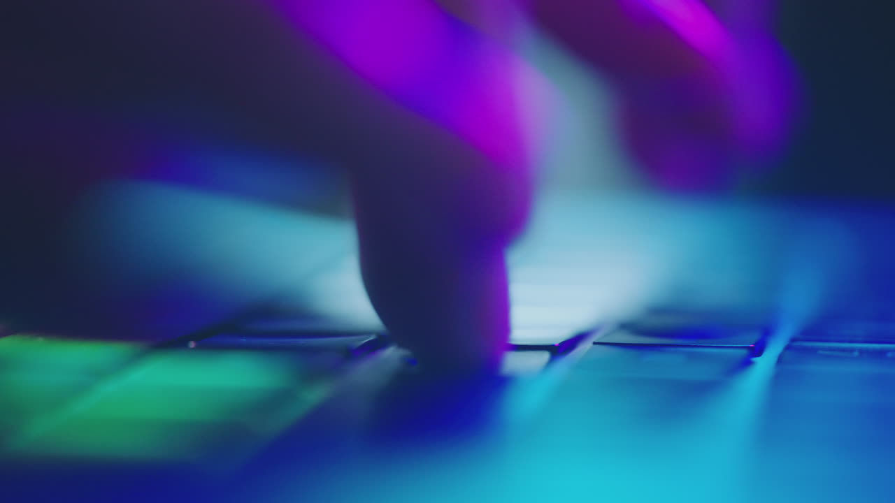 Close-up of hands typing on a laptop keyboard at night.