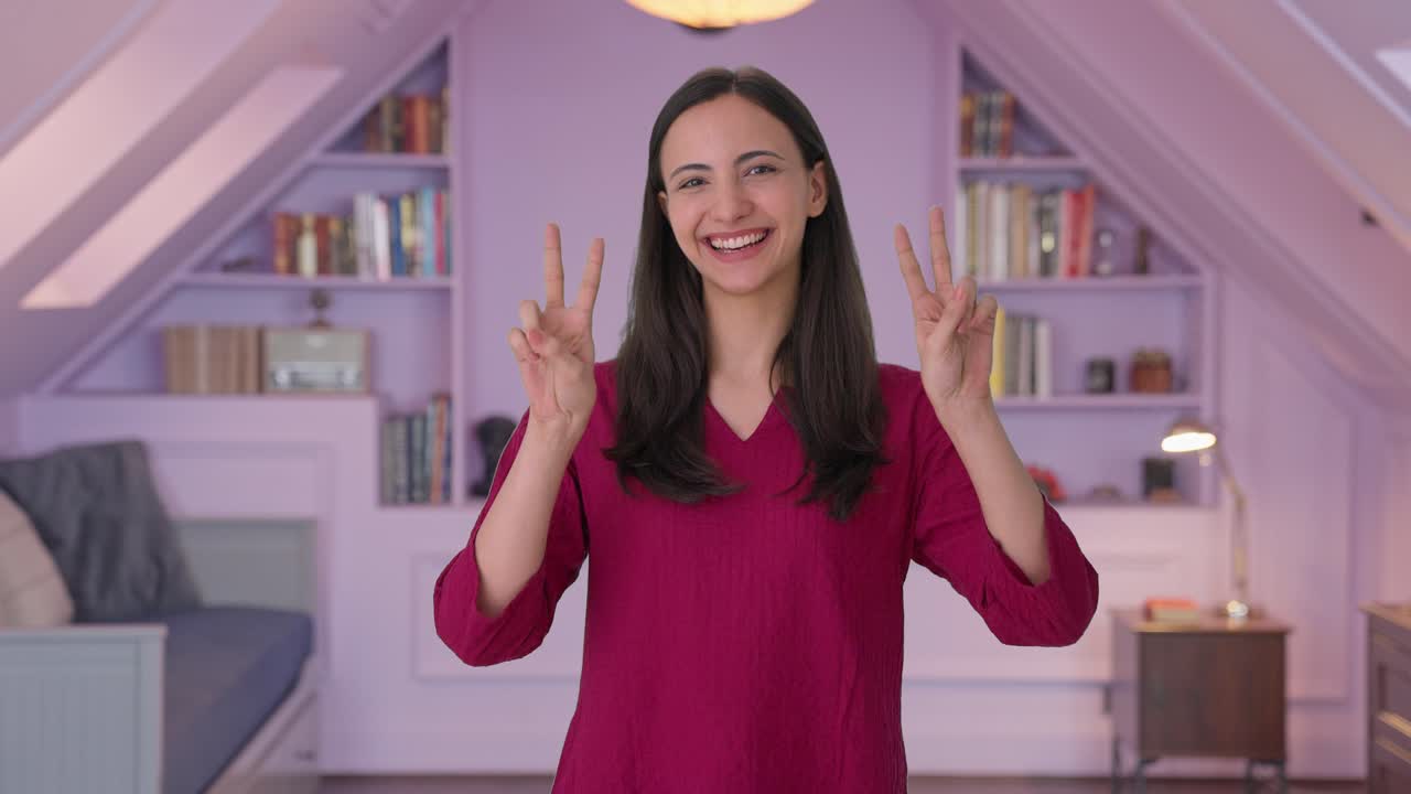 donna indiana felice che mostra il segno della vittoria