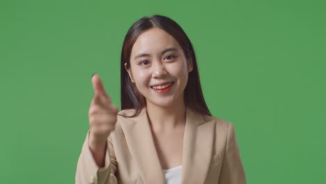 close up of asian business woman smiling and making honest gesture on green screen background in the studio