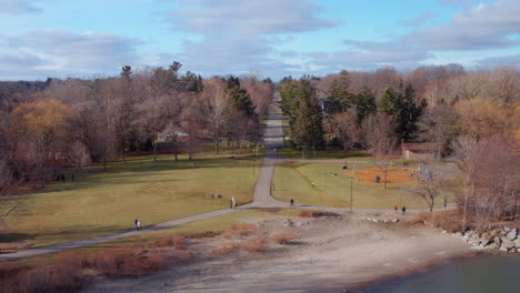 drone view of a lakeside park with a road vanishing off into the distance, pulling back over the water as seagulls fly around