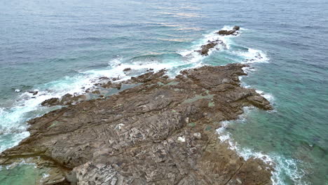 Vista-Aérea-De-Inclinación-Lineal-De-La-Costa-Rocosa-Con-Hierba-Verde