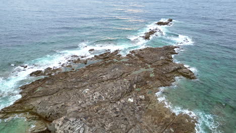 linear tilt aerial view of rocky coastline with green grass