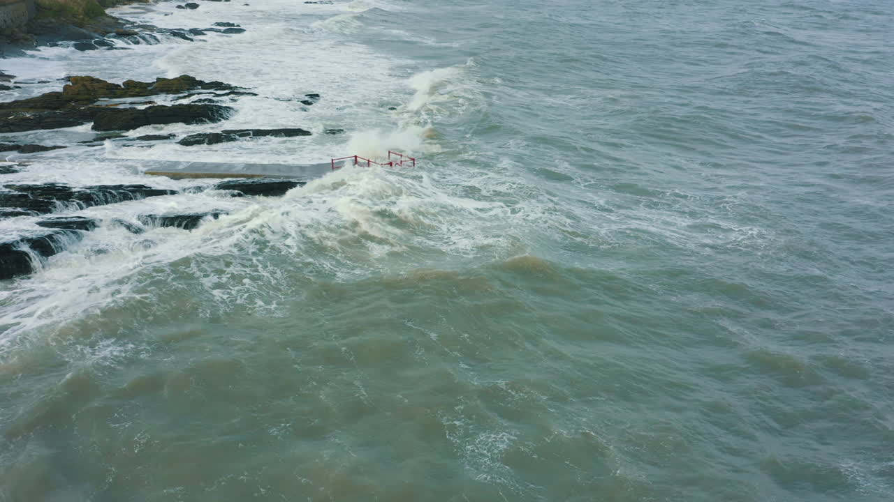 vista aérea de las olas rompiendo contra las rocas a lo largo de la costa