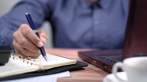 persona escribiendo en un cuaderno en un escritorio