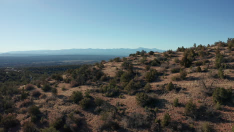 Aerial-moving-through-desert-hills-revealing-distant-mountain-range,-4K