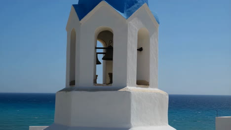 iconic white bell tower with blue dome against a clear sky and sea