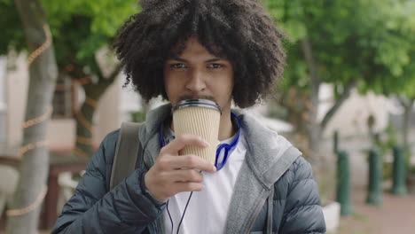 close up portrait of young mixed race man with afro hairstyle drinking coffee beverage smiling enjoying urban lifestyle