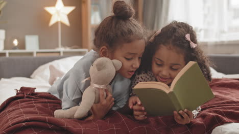 little sisters reading book in bed