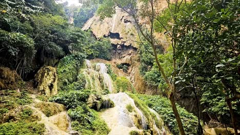 sai yok waterfalls cascading down the limestone rocks surrounded by lush vegetation in a national park in kanchanaburi province in thailand