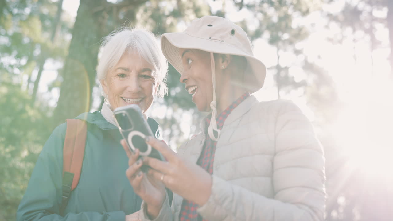두 명의 여성이 하이킹을 하고 전화를 사용하고 있습니다.